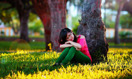 Slow: The Medicine of Slowing a young woman sitting and resting against a tree